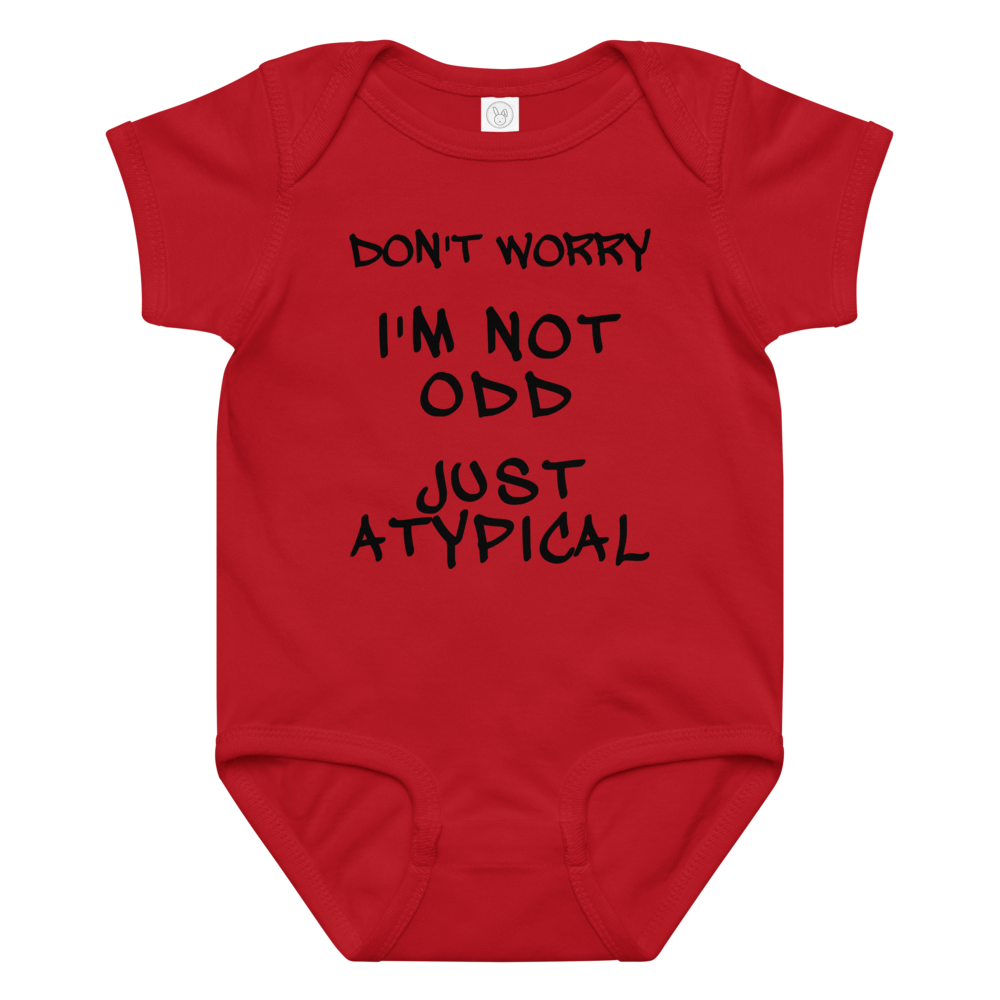 "Don't Worry I'm Not Odd Just Atypical" printed on a red baby jersey bodysuit laying on a flat surface amongst other clothes