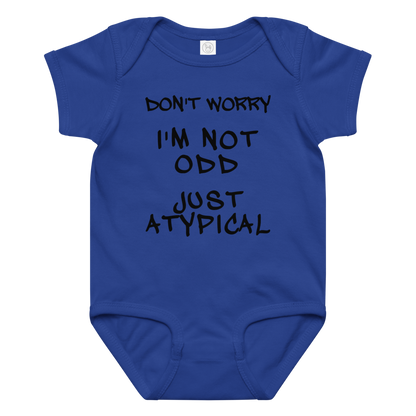 "Don't Worry I'm Not Odd Just Atypical" printed on a royal baby jersey bodysuit laying on a flat surface amongst other clothes