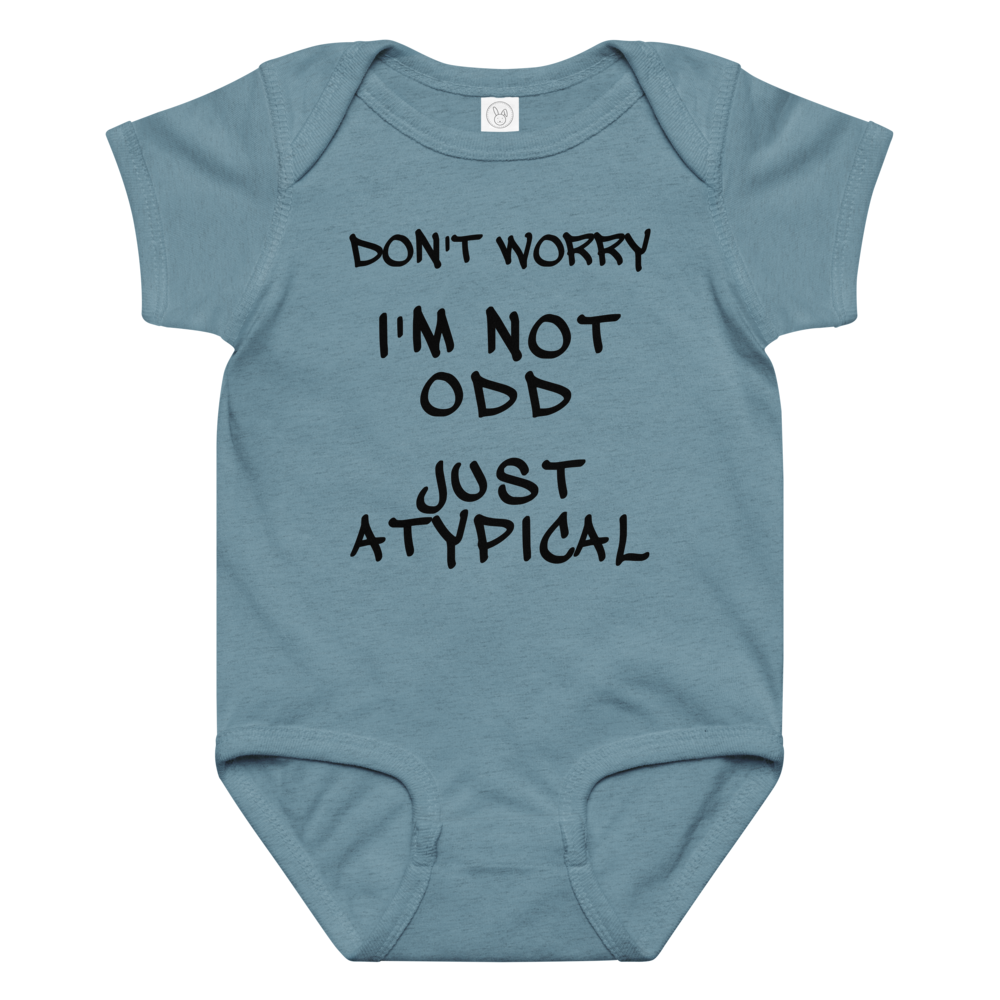 "Don't Worry I'm Not Odd Just Atypical" printed on a vintage indigo baby jersey bodysuit laying on a flat surface amongst other clothes