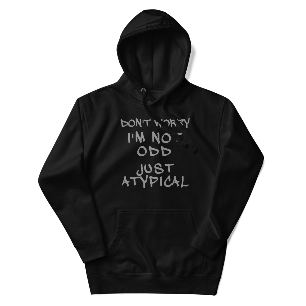 "Don't Worry I'm Not Odd Just Atypical" printed on a black unisex hoodie laying on a flat surface with the hood up