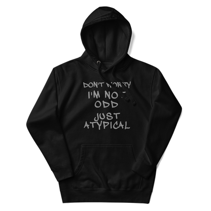 "Don't Worry I'm Not Odd Just Atypical" printed on a black unisex hoodie laying on a flat surface with the hood up