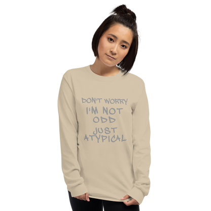 "Don't Worry I'm Not Odd Just Atypical" printed on a sand men's long sleeve shirt worn by a female