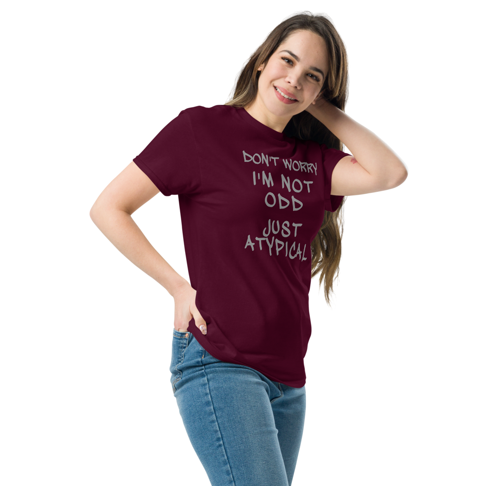 "Don't Worry I'm Not Odd Just Atypical" printed on a maroon unisex classic tee worn by a female