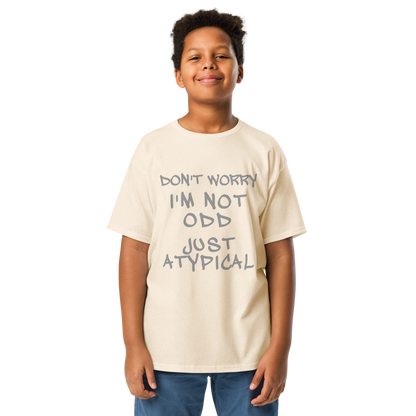 "Don't Worry I'm Not Odd Just Atypical" printed on a natural youth classic tee worn by a male