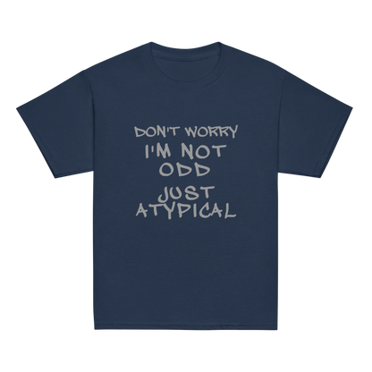 "Don't Worry I'm Not Odd Just Atypical" printed on a navy youth classic tee laying on a flat surface