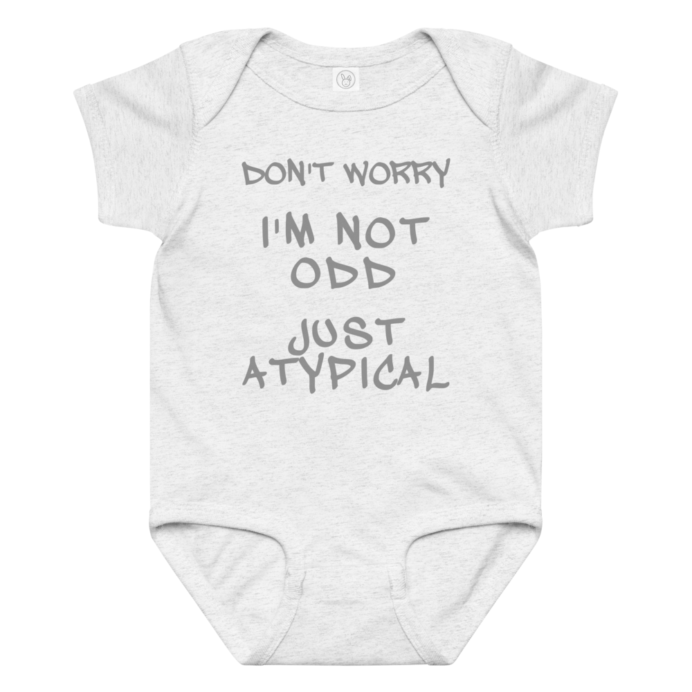 "Don't Worry I'm Not Odd Just Atypical" printed on a ash baby jersey bodysuit laying on a flat surface amongst other clothes