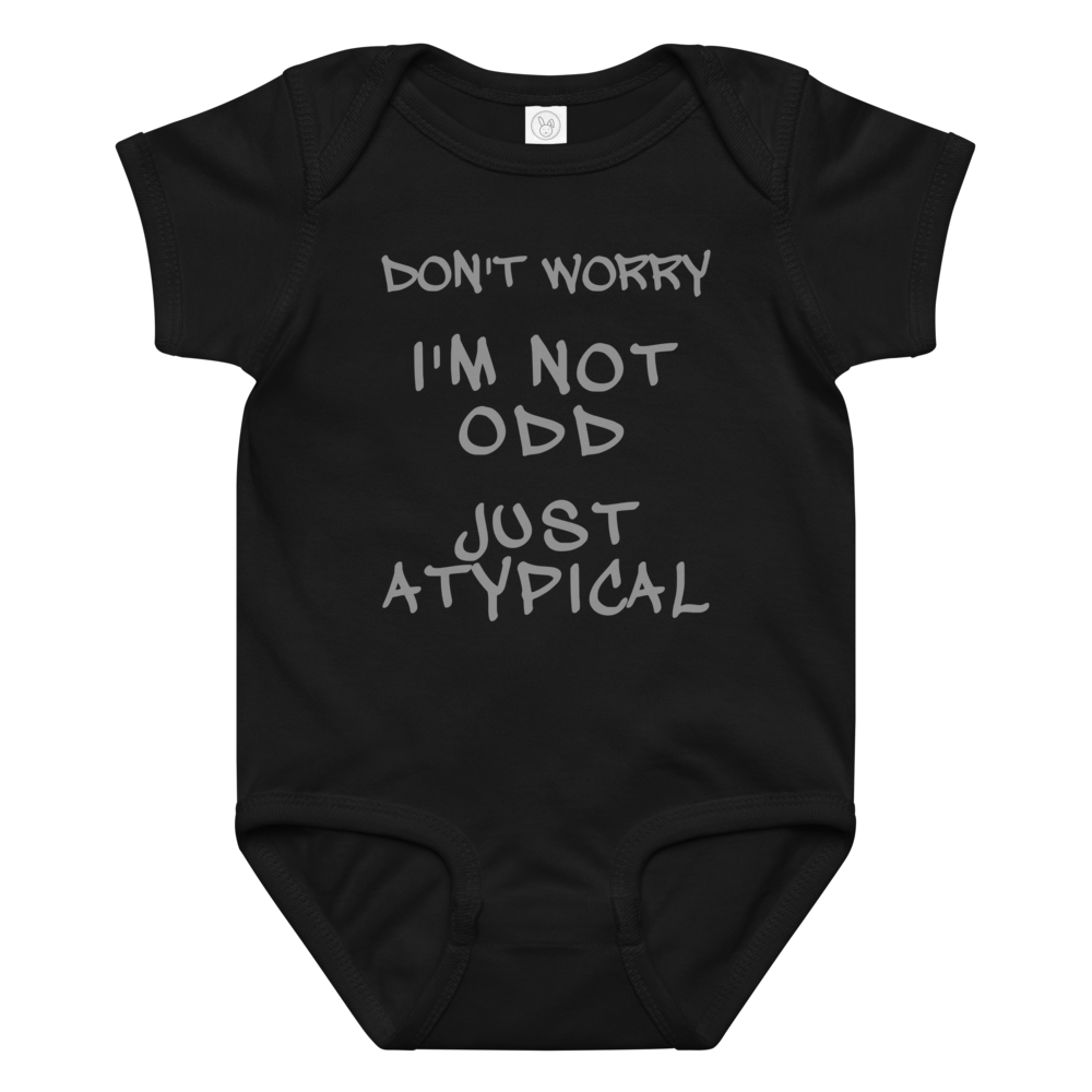 "Don't Worry I'm Not Odd Just Atypical" printed on a black baby jersey bodysuit laying on a flat surface amongst other clothes