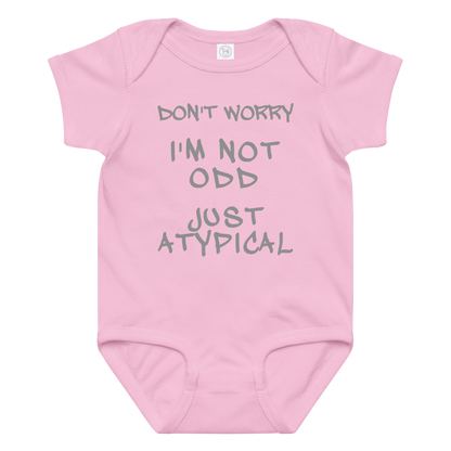 "Don't Worry I'm Not Odd Just Atypical" printed on a pink baby jersey bodysuit laying on a flat surface amongst other clothes