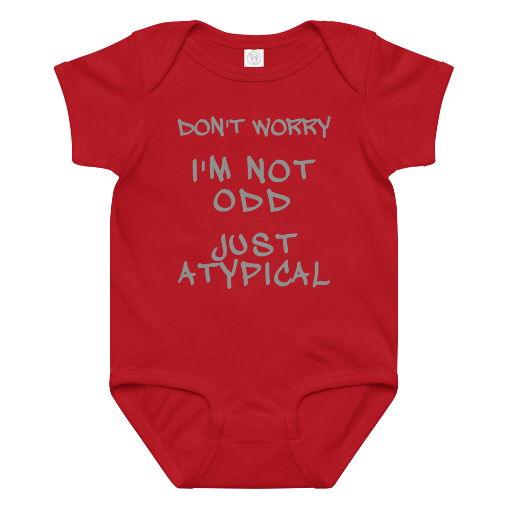 "Don't Worry I'm Not Odd Just Atypical" printed on a red baby jersey bodysuit laying on a flat surface amongst other clothes