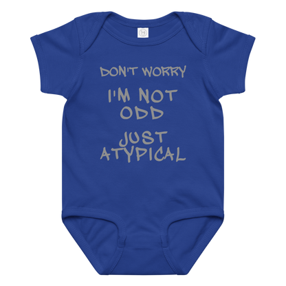 "Don't Worry I'm Not Odd Just Atypical" printed on a royal baby jersey bodysuit laying on a flat surface amongst other clothes
