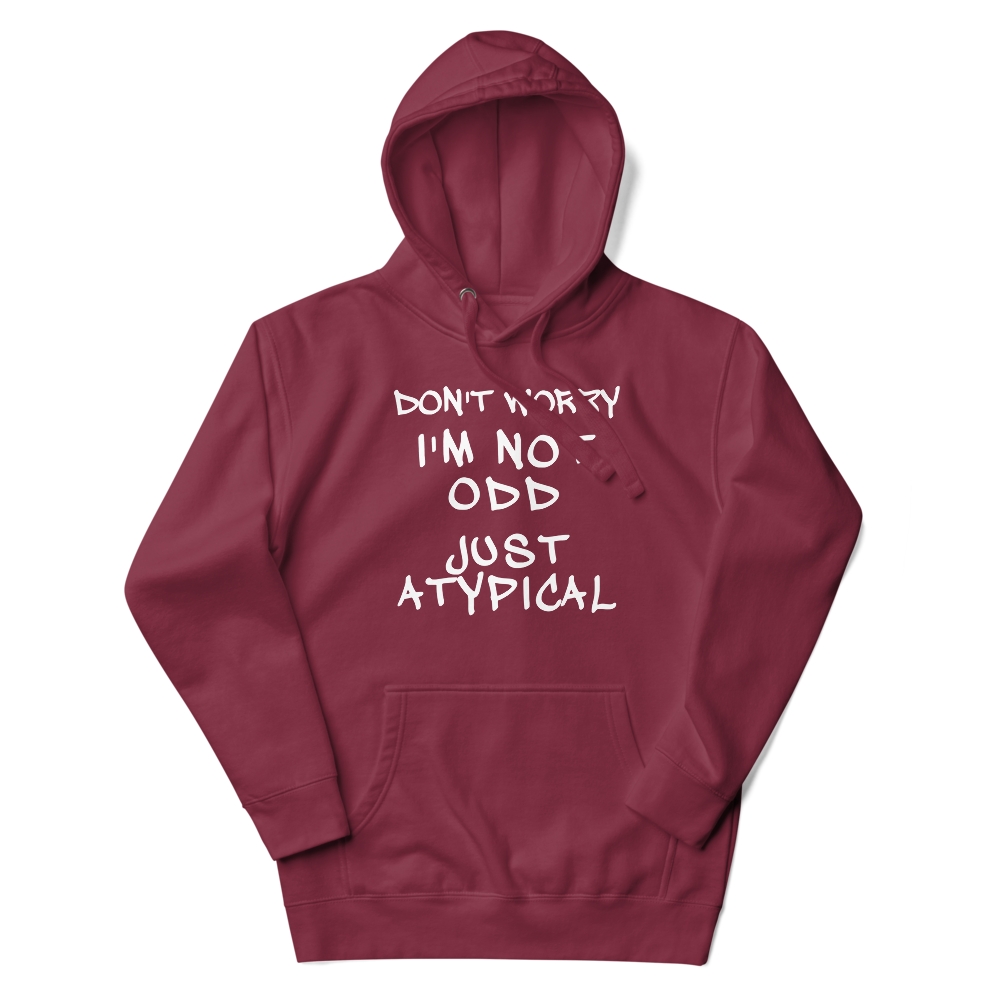 "Don't Worry I'm Not Odd Just Atypical" printed on a maroon unisex hoodie laying on a flat surface with the hood up