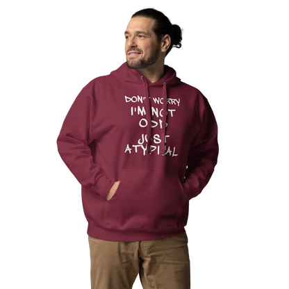 "Don't Worry I'm Not Odd Just Atypical" printed on a maroon unisex hoodie worn by a male