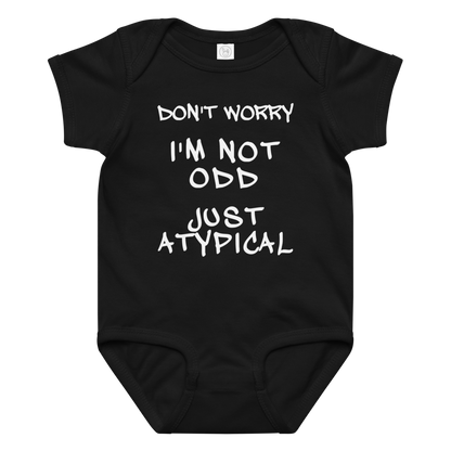 "Don't Worry I'm Not Odd Just Atypical" printed on a black baby jersey bodysuit laying on a flat surface amongst other clothes