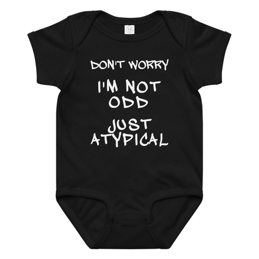 "Don't Worry I'm Not Odd Just Atypical" printed on a black baby jersey bodysuit laying on a flat surface amongst other clothes