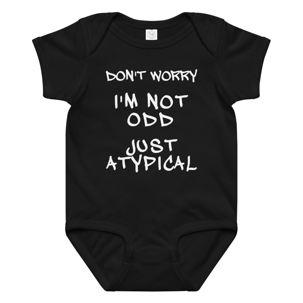 "Don't Worry I'm Not Odd Just Atypical" printed on a black baby jersey bodysuit laying on a flat surface amongst other clothes