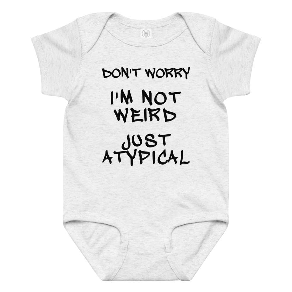 "Don't Worry I'm Not Weird Just Atypical" printed on a ash baby jersey bodysuit laying on a flat surface amongst other clothes