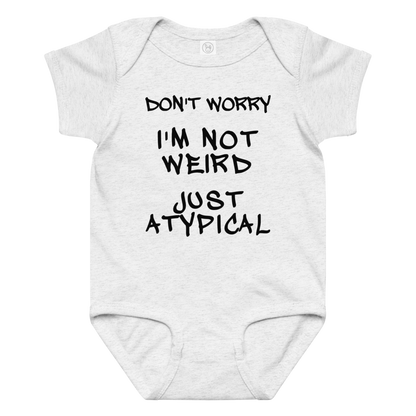 "Don't Worry I'm Not Weird Just Atypical" printed on a ash baby jersey bodysuit laying on a flat surface amongst other clothes