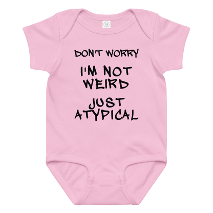"Don't Worry I'm Not Weird Just Atypical" printed on a pink baby jersey bodysuit laying on a flat surface amongst other clothes