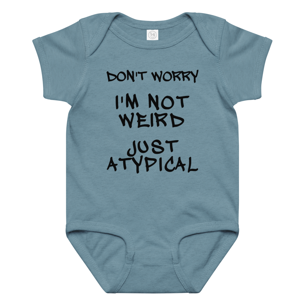 "Don't Worry I'm Not Weird Just Atypical" printed on a vintage indigo baby jersey bodysuit laying on a flat surface amongst other clothes