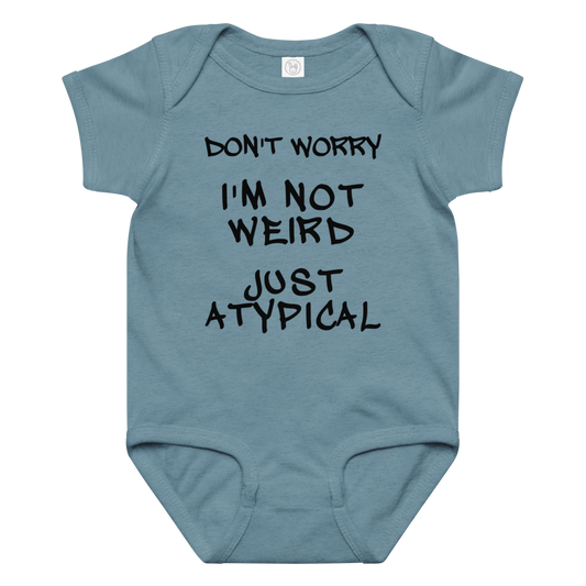 "Don't Worry I'm Not Weird Just Atypical" printed on a vintage indigo baby jersey bodysuit laying on a flat surface amongst other clothes