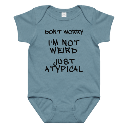 "Don't Worry I'm Not Weird Just Atypical" printed on a vintage indigo baby jersey bodysuit laying on a flat surface amongst other clothes