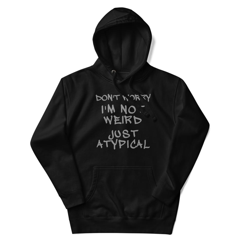 "Don't Worry I'm Not Weird Just Atypical" printed on a black unisex hoodie laying on a flat surface with the hood up