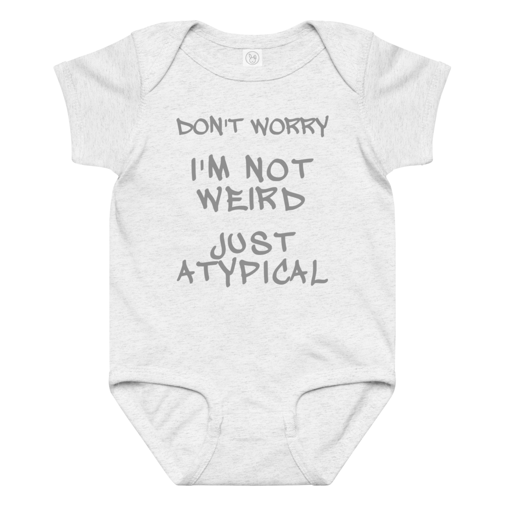 "Don't Worry I'm Not Weird Just Atypical" printed on a ash baby jersey bodysuit laying on a flat surface amongst other clothes