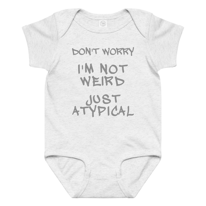 "Don't Worry I'm Not Weird Just Atypical" printed on a ash baby jersey bodysuit laying on a flat surface amongst other clothes