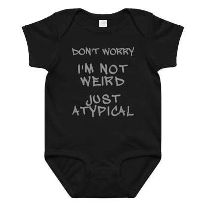"Don't Worry I'm Not Weird Just Atypical" printed on a black baby jersey bodysuit laying on a flat surface amongst other clothes