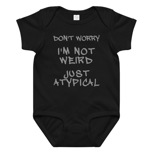 "Don't Worry I'm Not Weird Just Atypical" printed on a black baby jersey bodysuit laying on a flat surface amongst other clothes