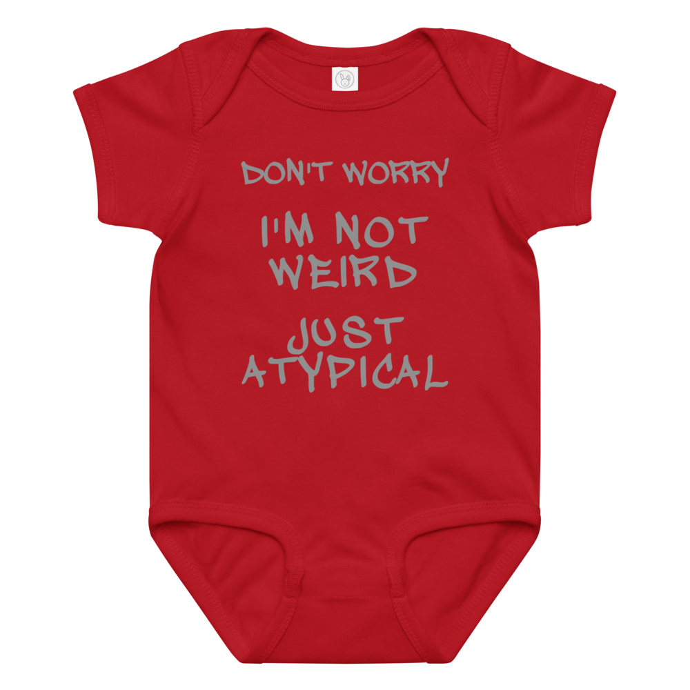 "Don't Worry I'm Not Weird Just Atypical" printed on a red baby jersey bodysuit laying on a flat surface amongst other clothes