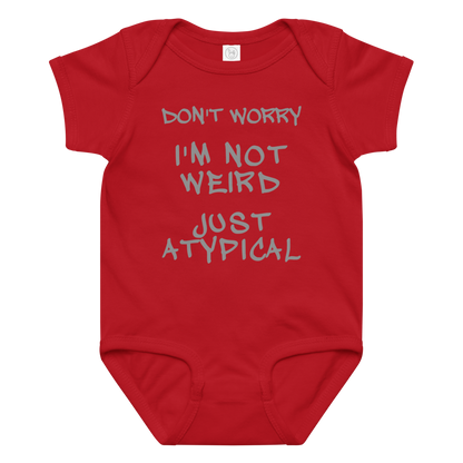 "Don't Worry I'm Not Weird Just Atypical" printed on a red baby jersey bodysuit laying on a flat surface amongst other clothes