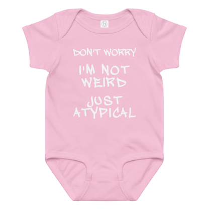 "Don't Worry I'm Not Weird Just Atypical" printed on a pink baby jersey bodysuit laying on a flat surface amongst other clothes