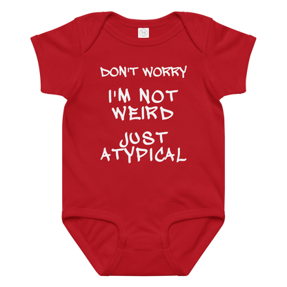 "Don't Worry I'm Not Weird Just Atypical" printed on a red baby jersey bodysuit laying on a flat surface amongst other clothes
