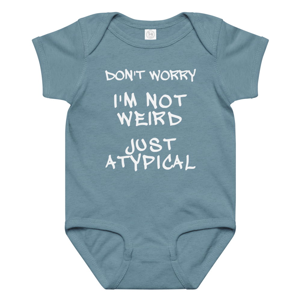 "Don't Worry I'm Not Weird Just Atypical" printed on a vintage indigo baby jersey bodysuit laying on a flat surface amongst other clothes