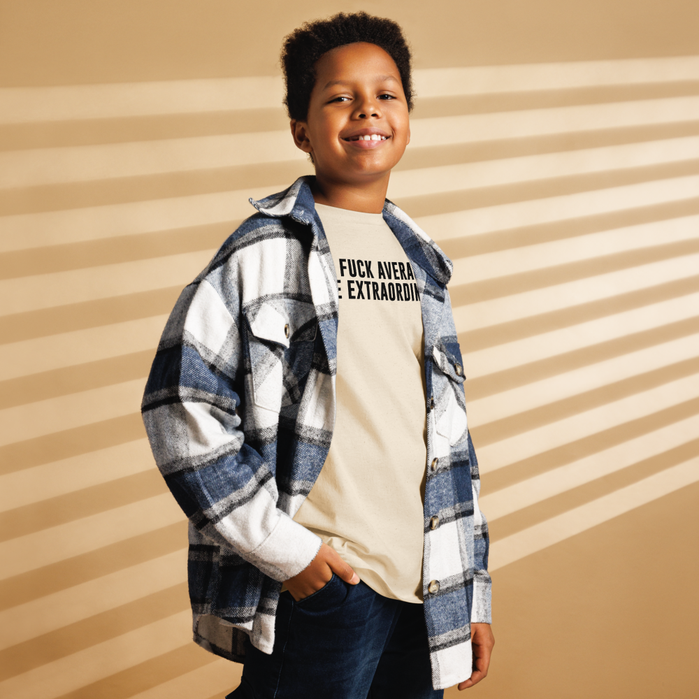 "Fuck Average, Be Extraordinary!" printed on a natural youth classic tee worn by a male also wearing a jacket