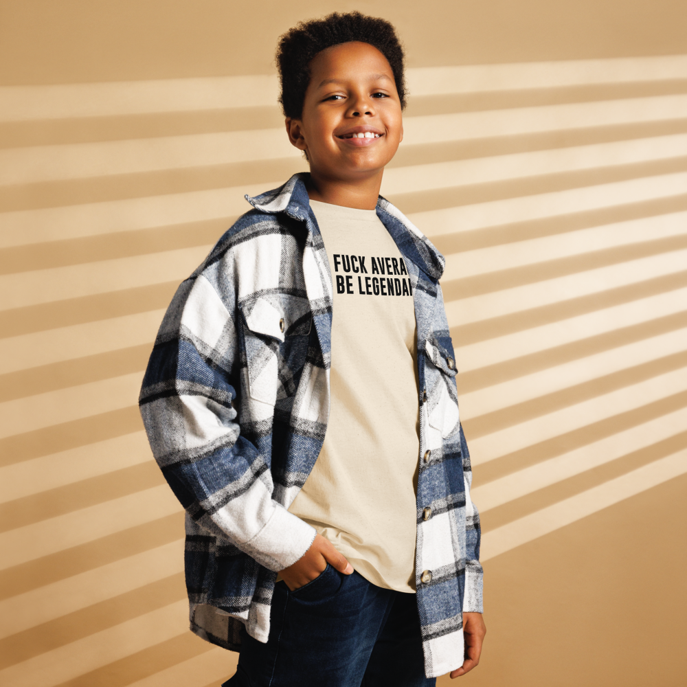 "Fuck Average, Be Legendary!" printed on a natural youth classic tee worn by a male also wearing a jacket