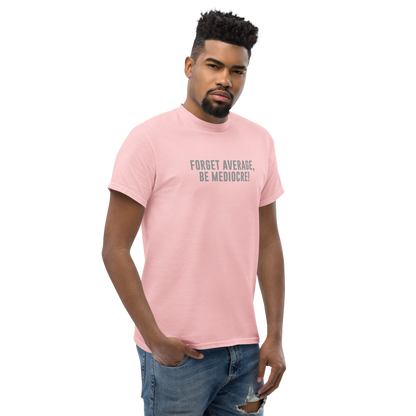 "Forget Average, Be Mediocre!" printed on a light pink unisex classic tee worn by a male