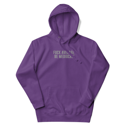 "Fuck Average, Be Mediocre!" printed on a purple unisex hoodie laying on a flat surface with the hood up
