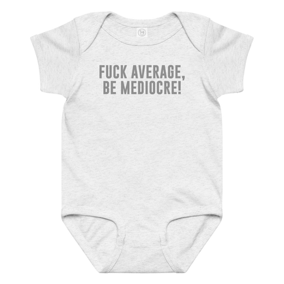 "Fuck Average, Be Mediocre!" printed on a ash baby jersey bodysuit laying on a flat surface amongst other clothes
