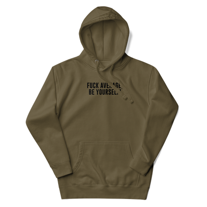 "Fuck Average, Be Yourself!" printed on a military green unisex hoodie laying on a flat surface with the hood up