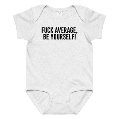"Fuck Average, Be Yourself!" printed on a ash baby jersey bodysuit laying on a flat surface amongst other clothes