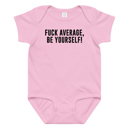 "Fuck Average, Be Yourself!" printed on a pink baby jersey bodysuit laying on a flat surface amongst other clothes