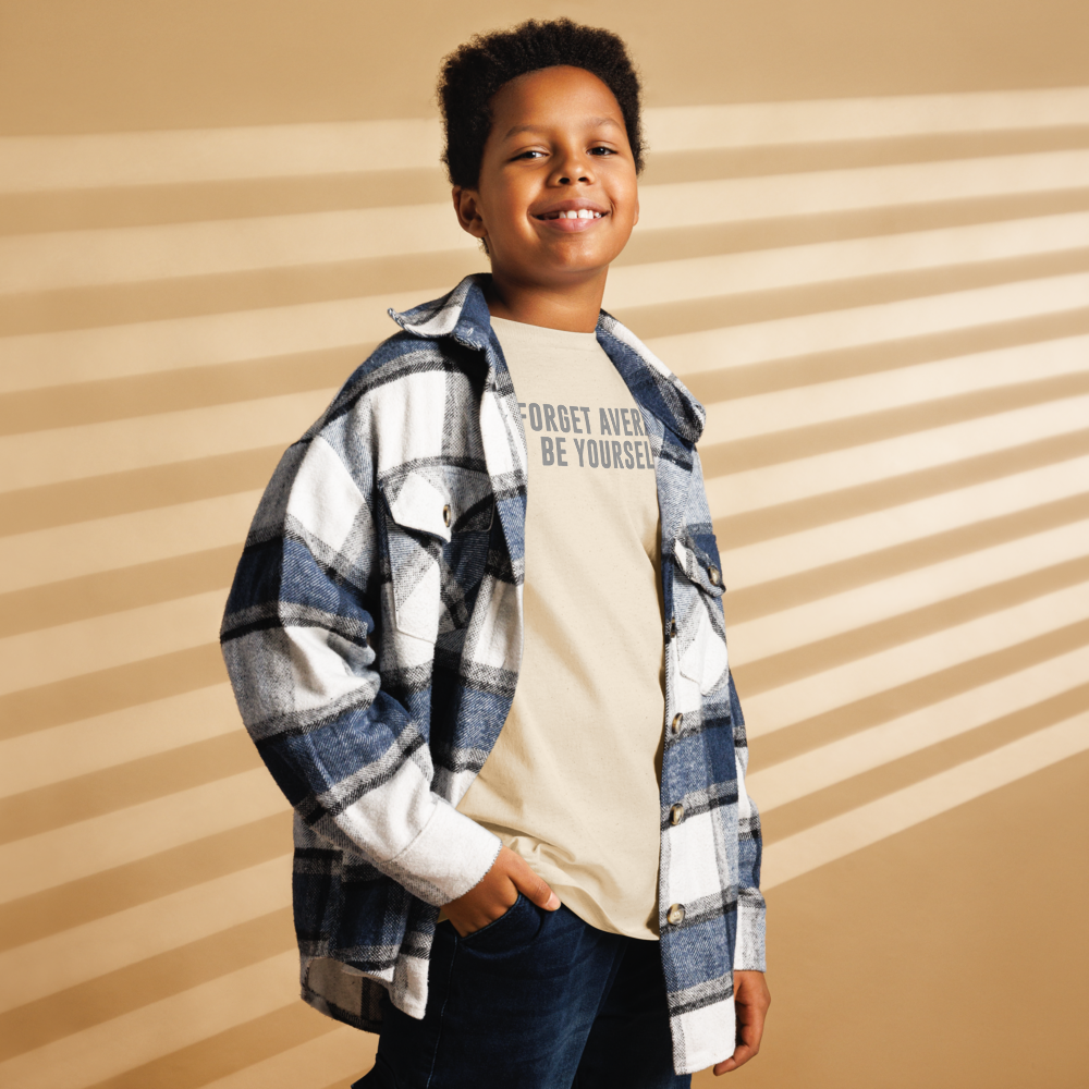 "Forget Average, Be Yourself!" printed on a natural youth classic tee worn by a male also wearing a jacket