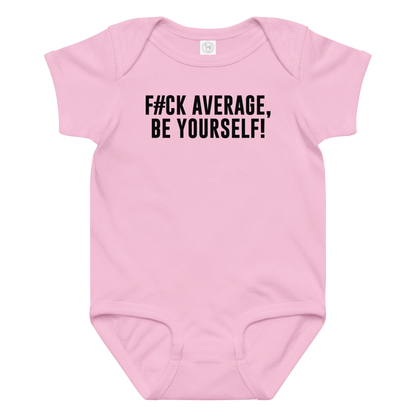 "F#Ck Average, Be Yourself!" printed on a pink baby jersey bodysuit laying on a flat surface amongst other clothes