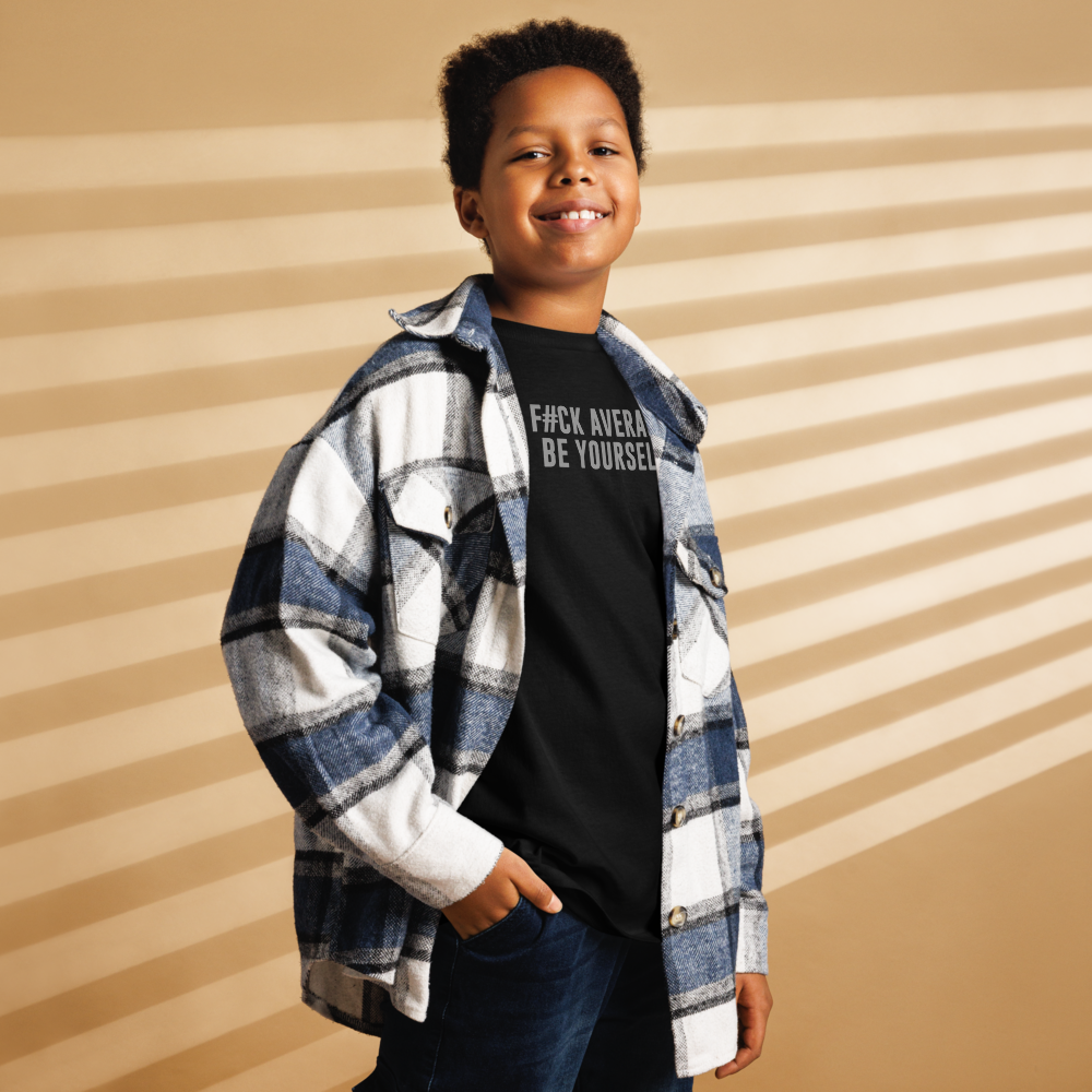 "F#Ck Average, Be Yourself!" printed on a black youth classic tee worn by a male also wearing a jacket