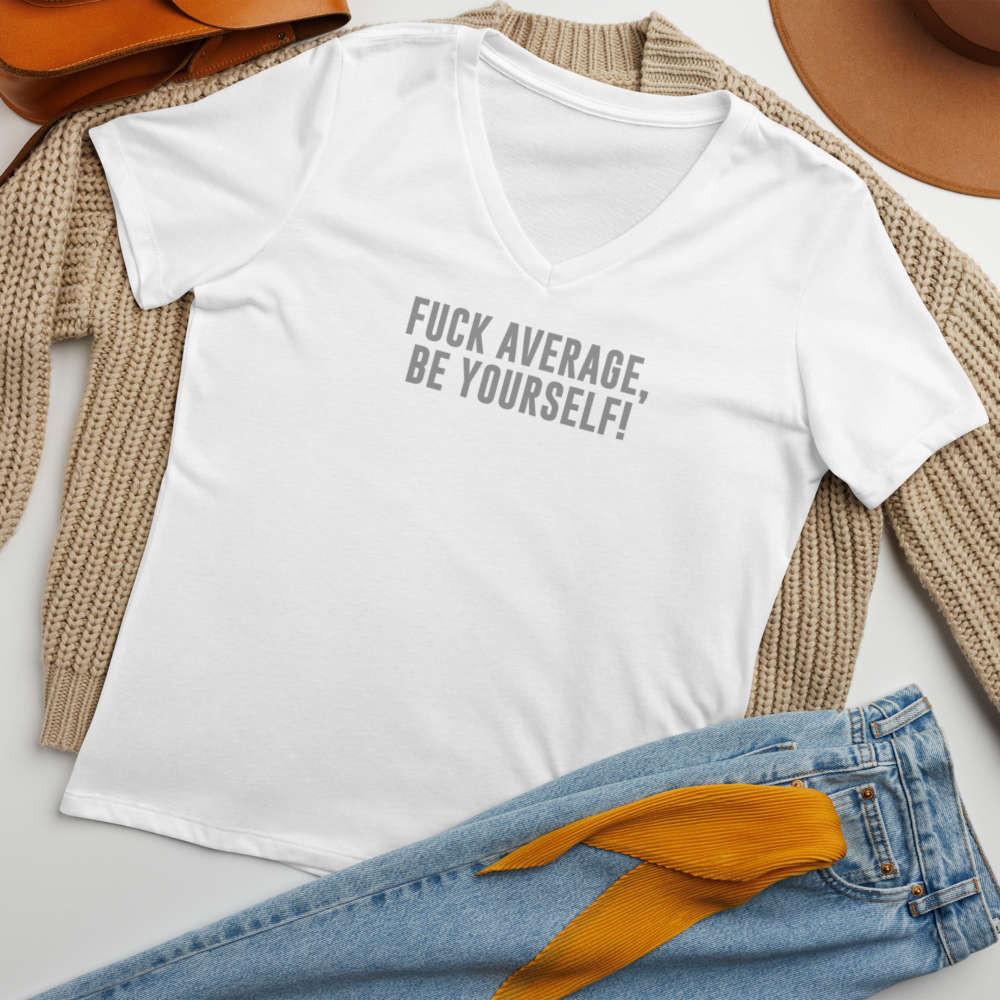 "Fuck Average, Be Yourself!" printed on a solid white blend women's relaxed v-neck t-shirt laying on a flat surface amongst other clothes