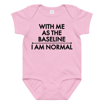 "With me as the baseline, I am normal" printed on a pink baby jersey bodysuit laying on a flat surface amongst other clothes