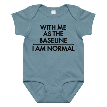 "With me as the baseline, I am normal" printed on a vintage indigo baby jersey bodysuit laying on a flat surface amongst other clothes
