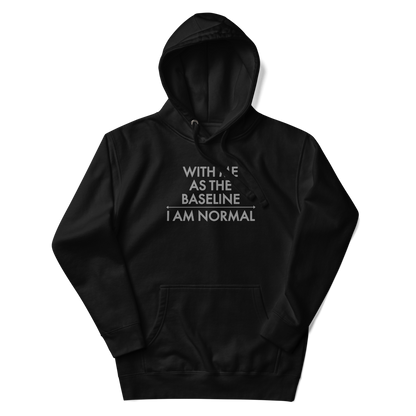 "With me as the baseline, I am normal" printed on a black unisex hoodie laying on a flat surface with the hood up